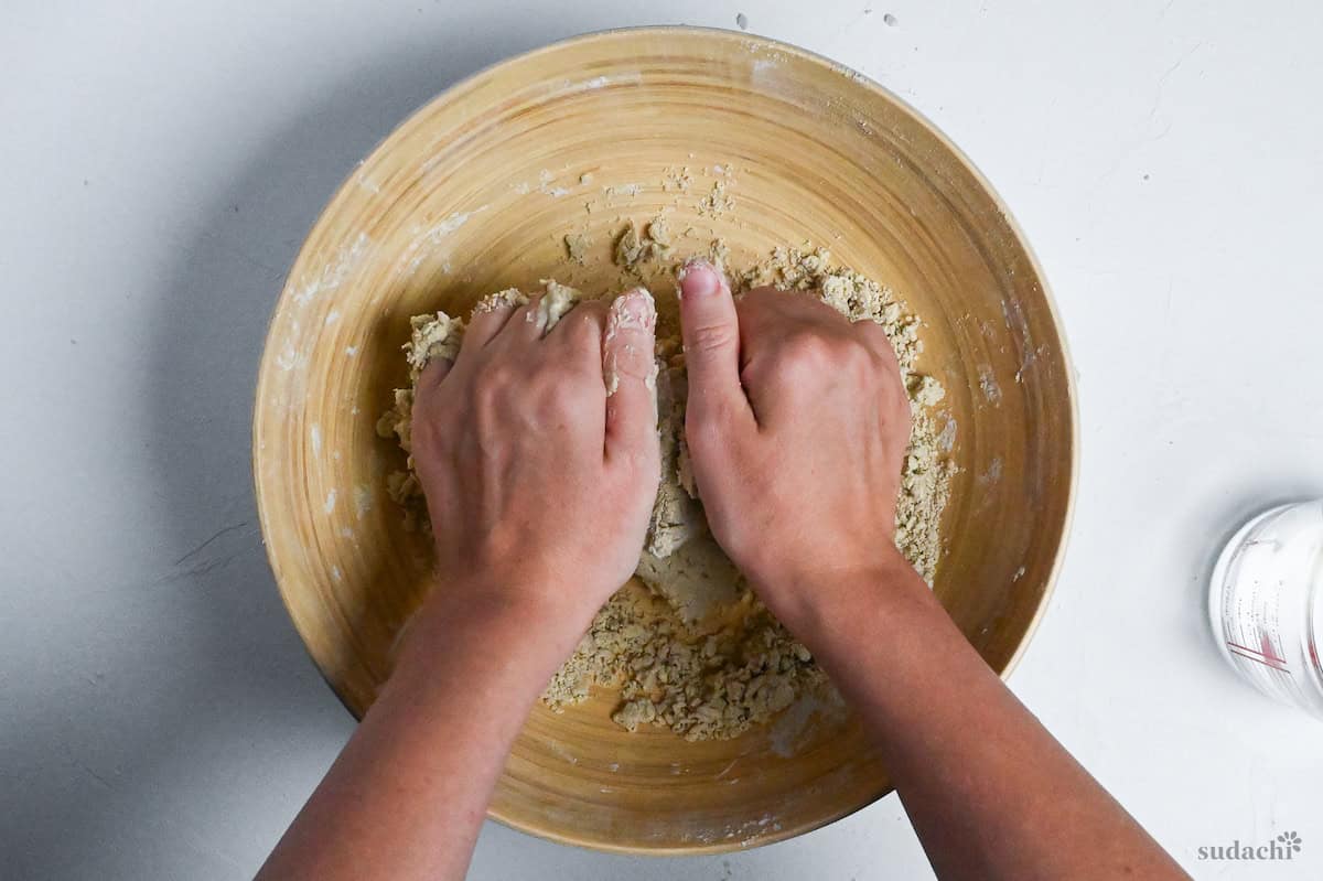 kneading soba noodle dough in a large wooden bowl