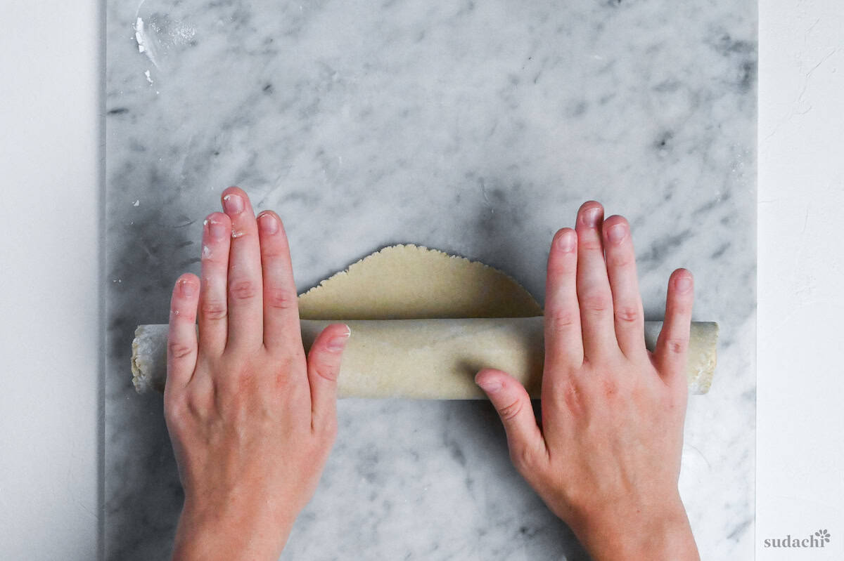 rolling soba noodle dough around a wooden rolling pin