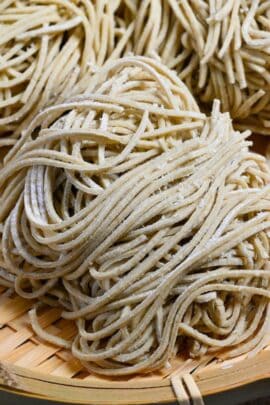 three bundles of homemade soba noodles on a bamboo tray