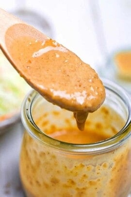 Japanese sesame dressing in a glass jar being scooped with a wooden spoon