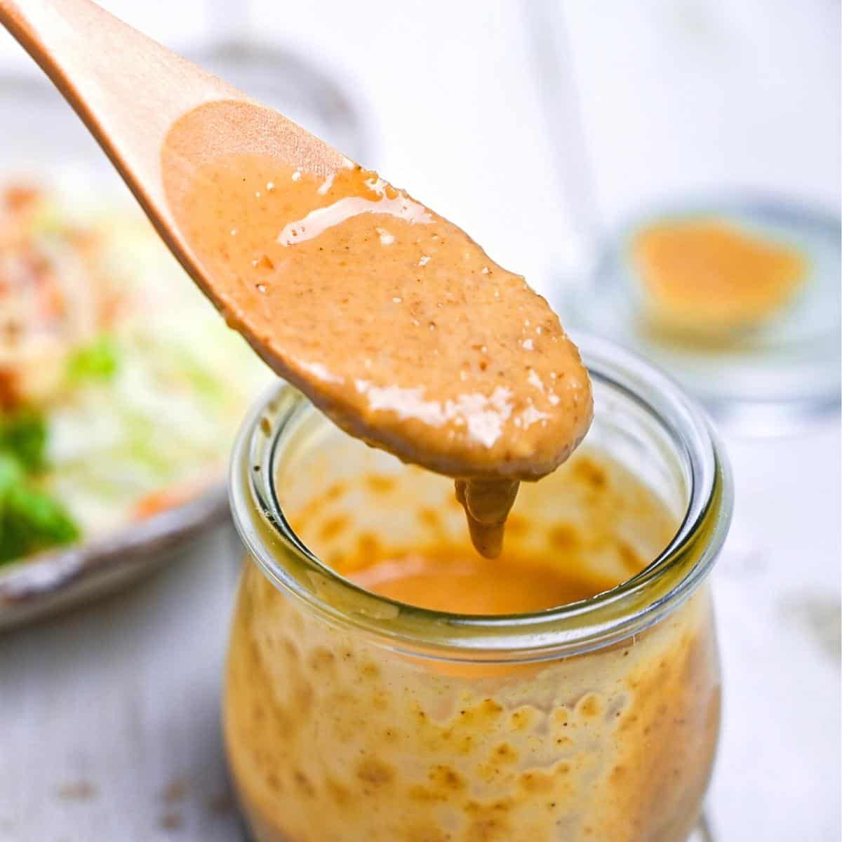 Japanese sesame dressing in a glass jar being scooped with a wooden spoon