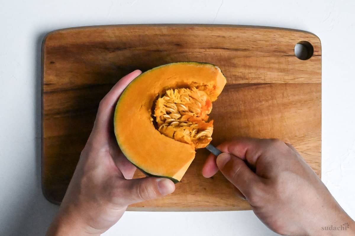 scooping seeds out of kabocha with a spoon