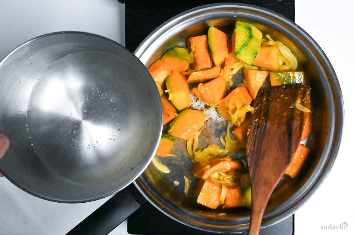 adding kombu dashi to softened kabocha and onion in a stainless steel pan