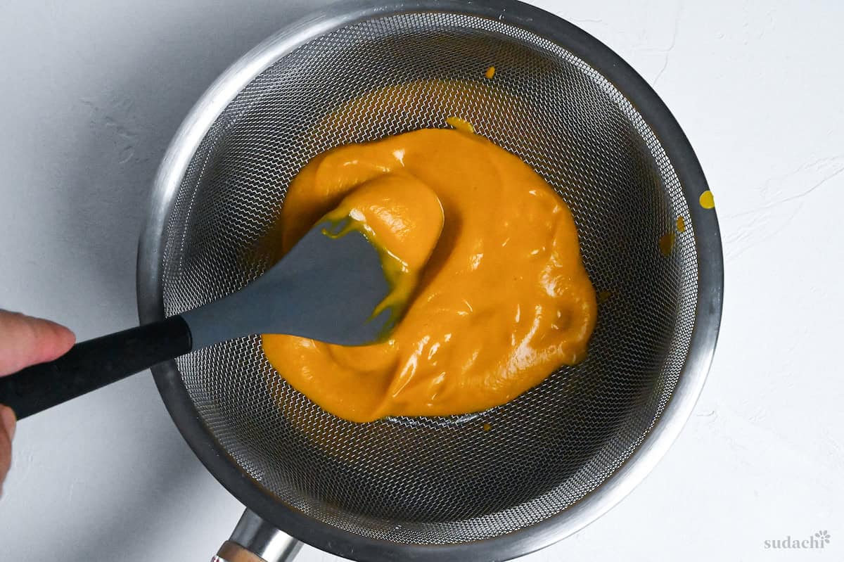 straining kabocha soup through a mesh sieve