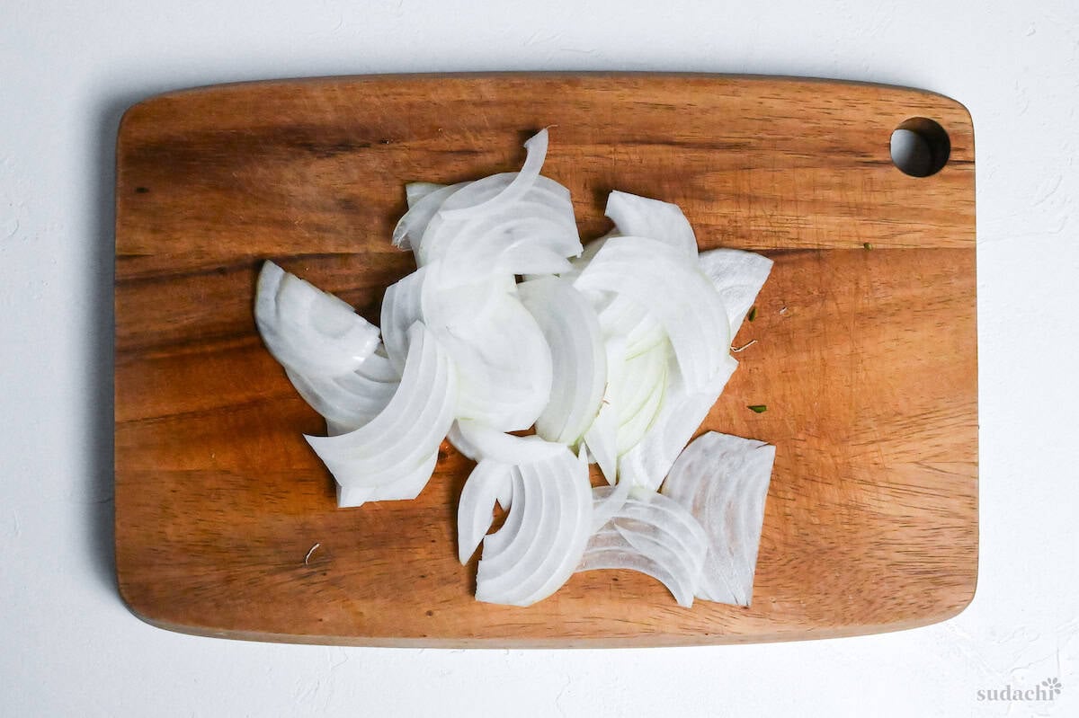 thinly sliced onion on a wooden cutting board