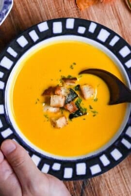 Japanese style kabocha soup topped with homemade croutons and kabocha skin in a white bowl with blue patterned rim