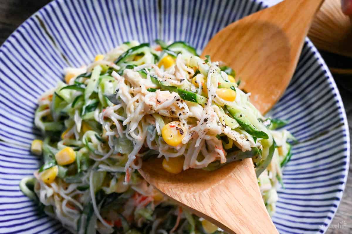 kani salad held up with wooden salad servers