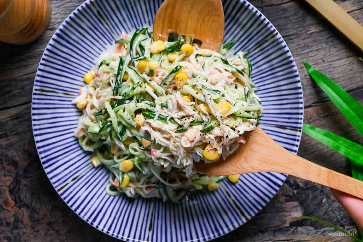 kani salad held up with wooden salad servers