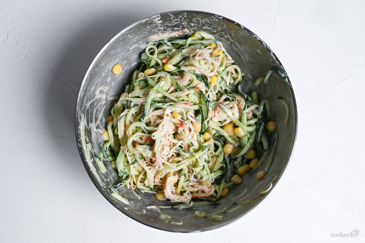 kani salad mixed in a steel mixing bowl on a white background