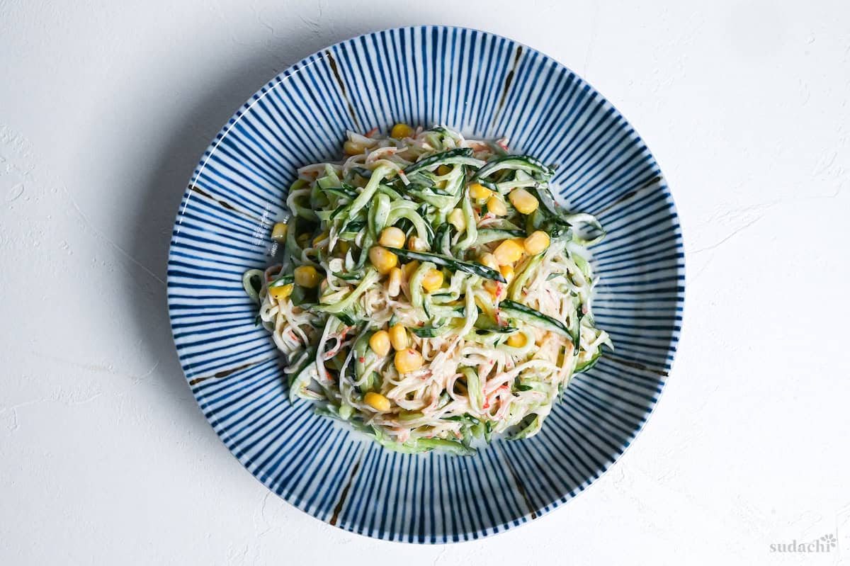 kani salad on a white and blue striped plate on a white background