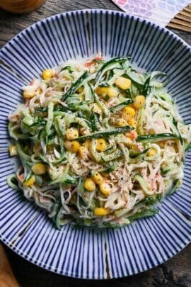 Kani Salad (Imitation Crab Salad with Wasabi Mayo Dressing) on a white plate with blue stripes on a wooden background top down