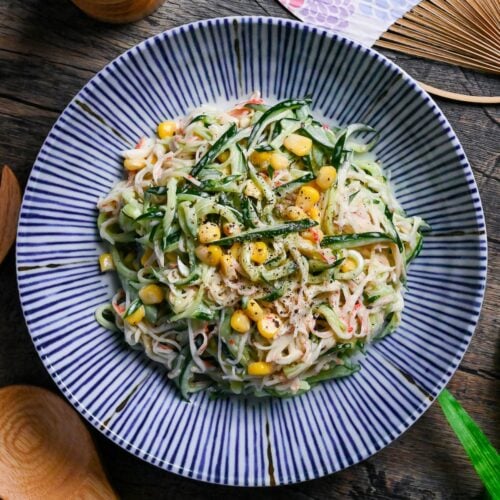 Kani Salad (Imitation Crab Salad with Wasabi Mayo Dressing) on a white plate with blue stripes on a wooden background top down