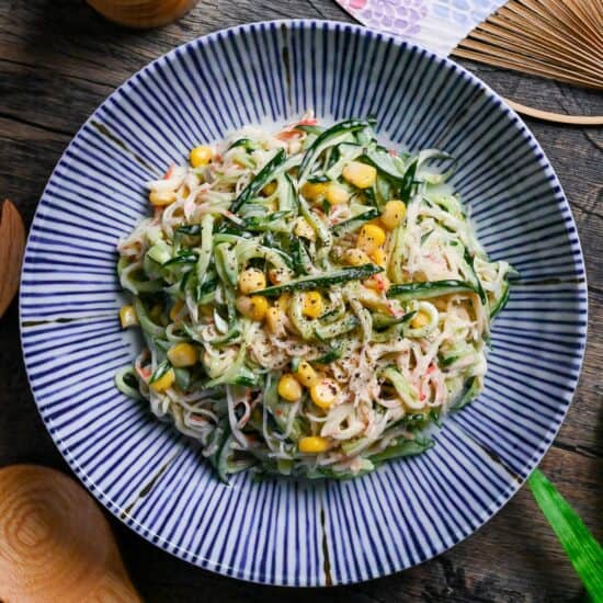 Kani Salad (Imitation Crab Salad with Wasabi Mayo Dressing) on a white plate with blue stripes on a wooden background top down