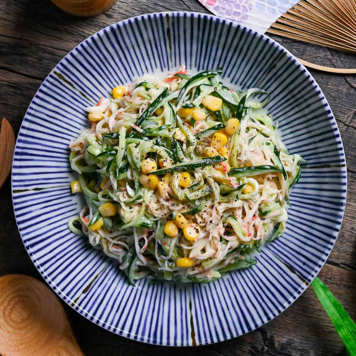 Kani Salad (Imitation Crab Salad with Wasabi Mayo Dressing) on a white plate with blue stripes on a wooden background top down