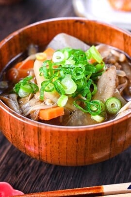 Japanese vegetable soup "kenchin jiru" served in a wooden bowl and topped with chopped spring onions