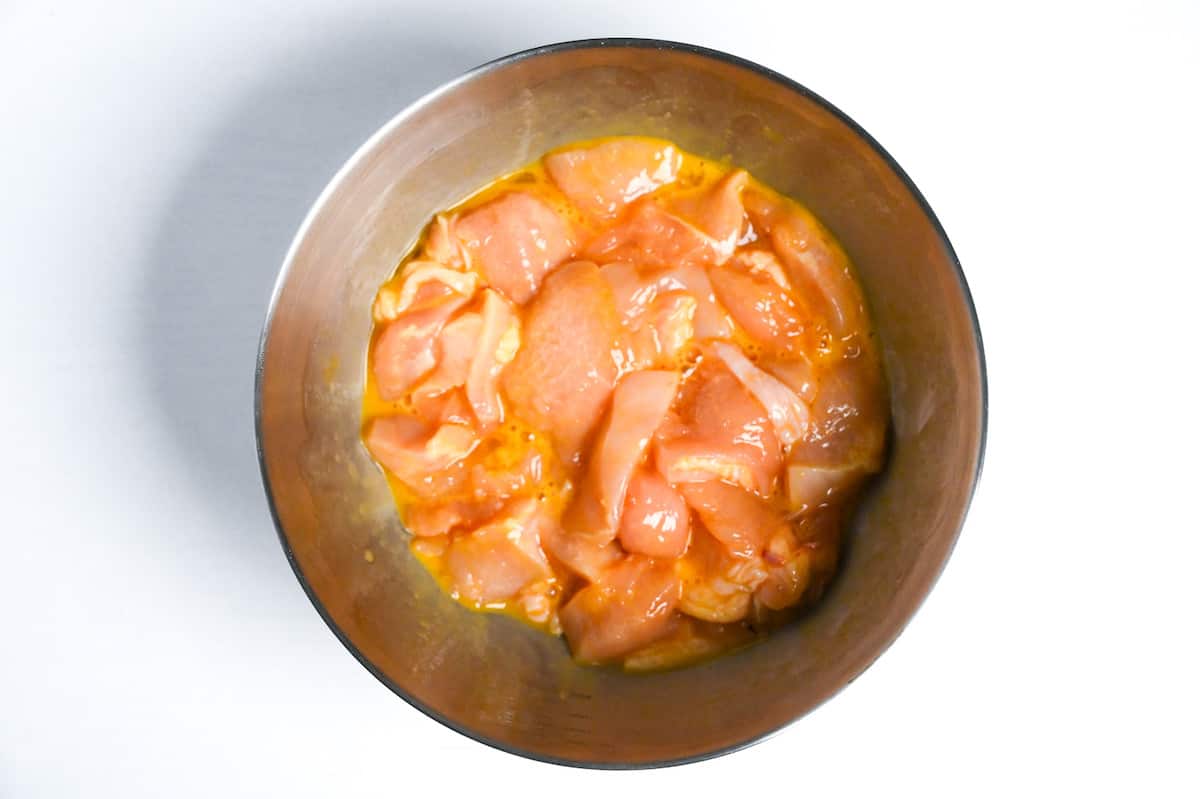 chicken breast pieces in egg in a mixing bowl