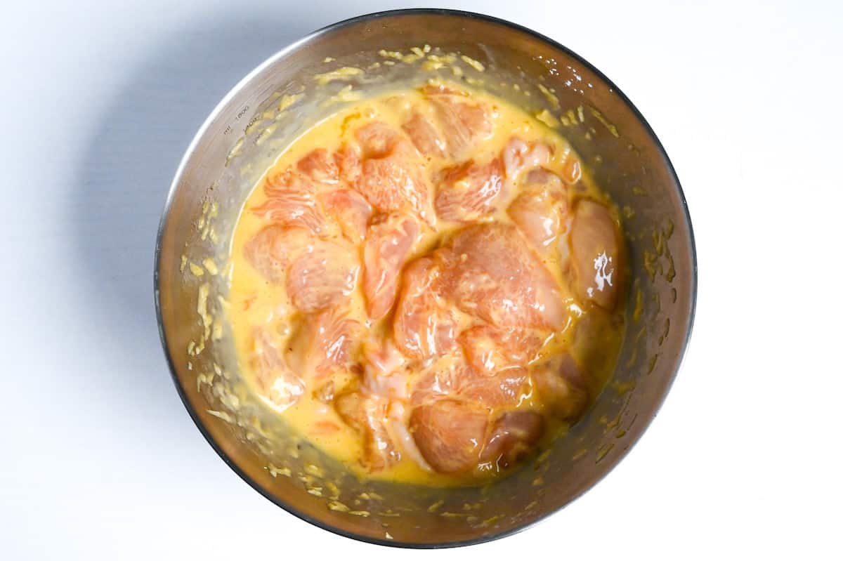 chicken breast pieces in egg and condiments in a mixing bowl