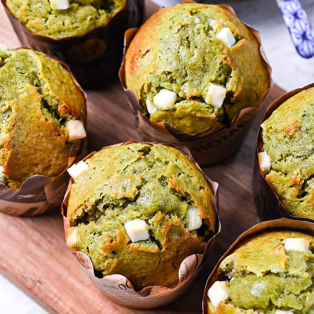 Matcha muffins with white chocolate chips on a wooden chopping board