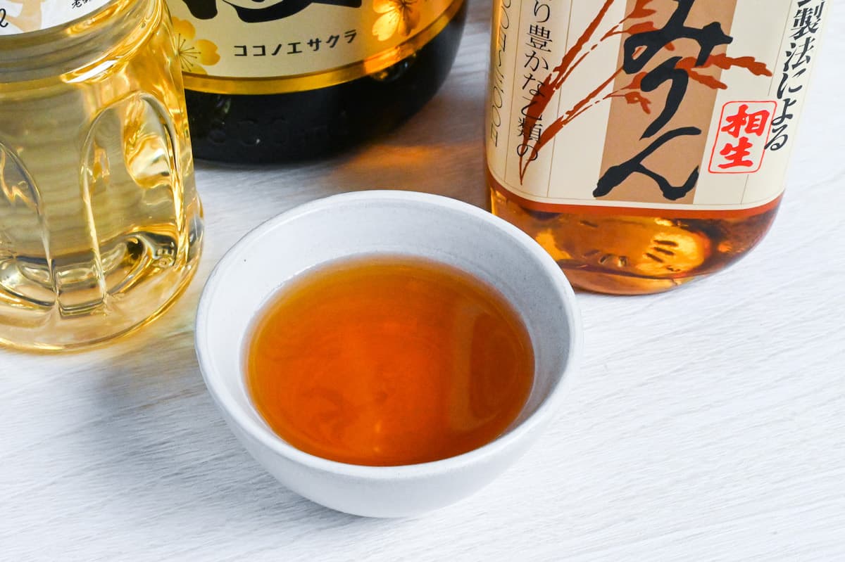 Bottles of Japanese hon mirin (Sweet rice wine seasoning) with some poured in a small white bowl