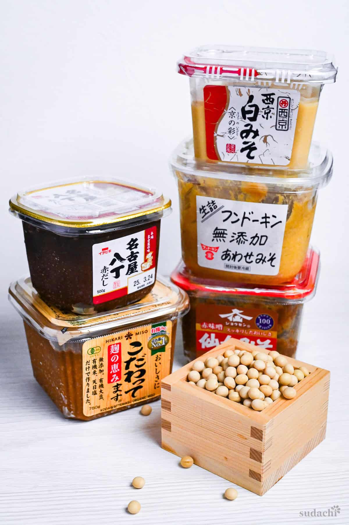 boxes of miso stacked up with a small wooden box of soybeans in the foreground