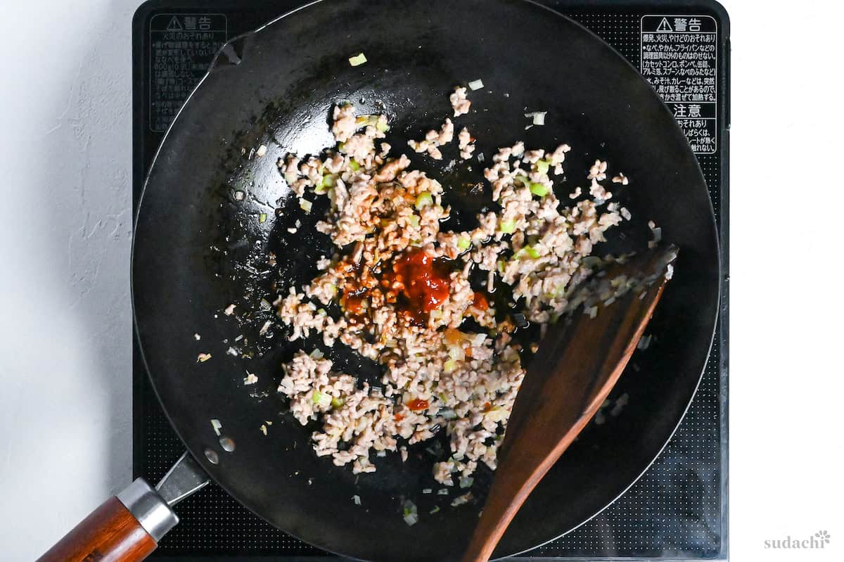 fried aromatics and browned pork mince in a wok with condiments to flavor