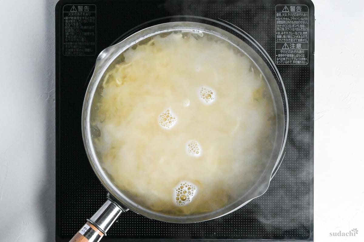 homemade egg ramen noodles boiling in a pot of water on the stove top