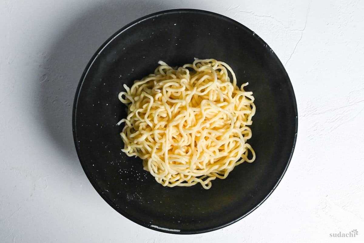 cooked egg ramen noodles in a black bowl on a white background