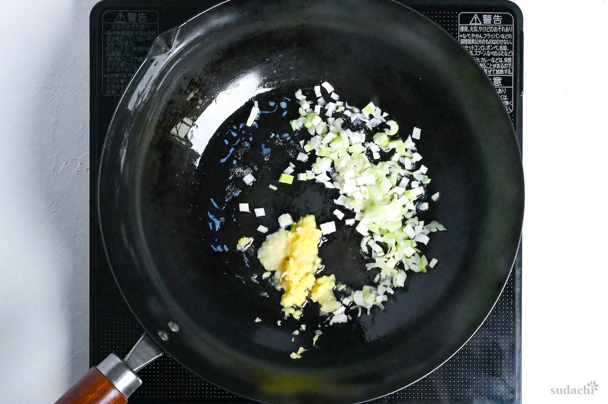 frying grated ginger, grated garlic and finely diced Japanese leek in butter and lard in a wok on the stove top