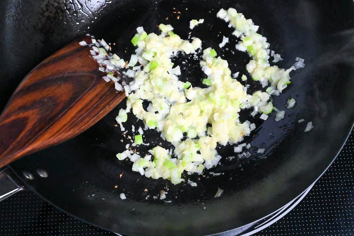 grated garlic, grated ginger and finely diced Japanese leek in a wok on the stove top