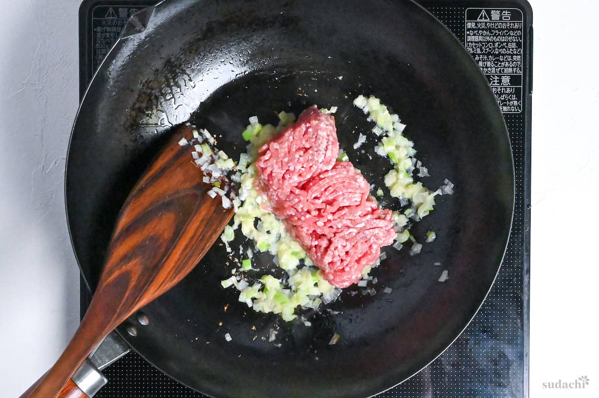 ground pork added to a wok with fried aromatics