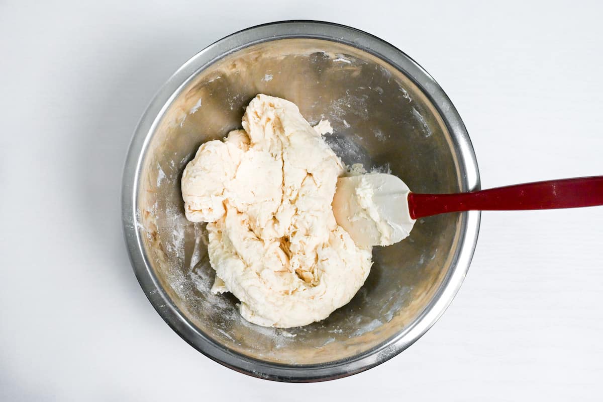 wet and dry ingredients combined to form a rough bread dough in a steel mixing bowl