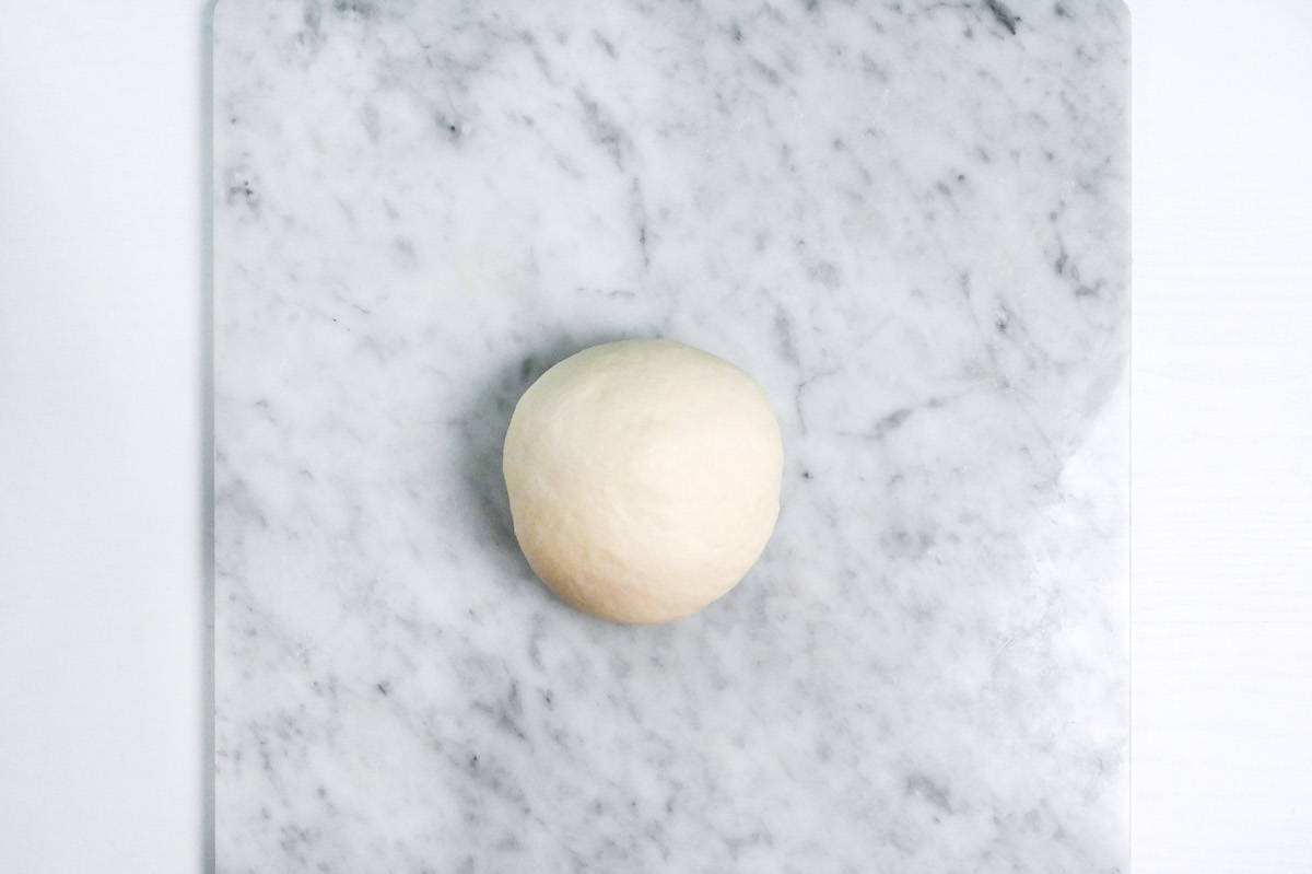 Nama shokupan dough rolled into a smooth board on a marble kneading board