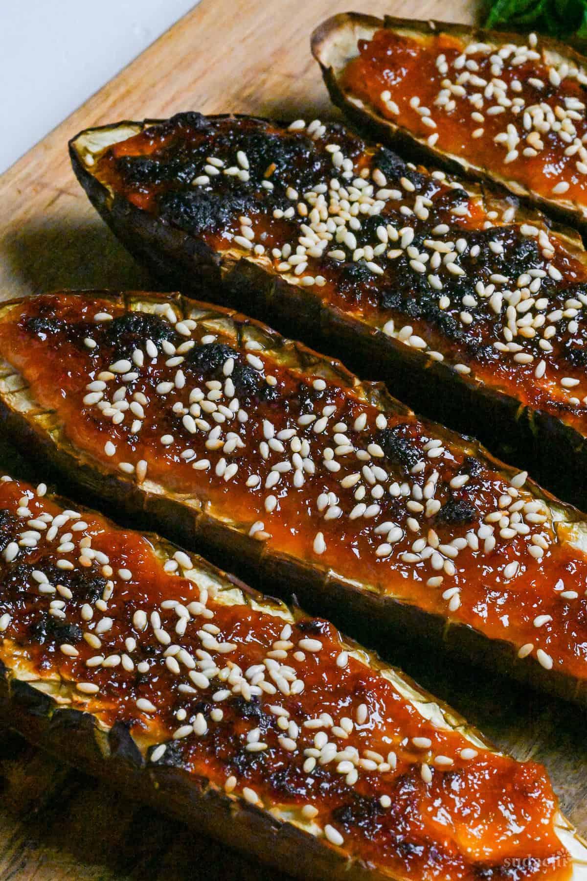 Nasu dengaku (Japanese miso-glazed eggplant) sprinkled with sesame seeds on a wooden chopping board