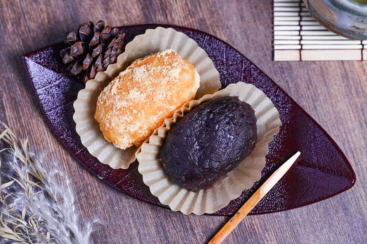 red bean and kinako ohagi on a red leaf-shaped plate with green tea