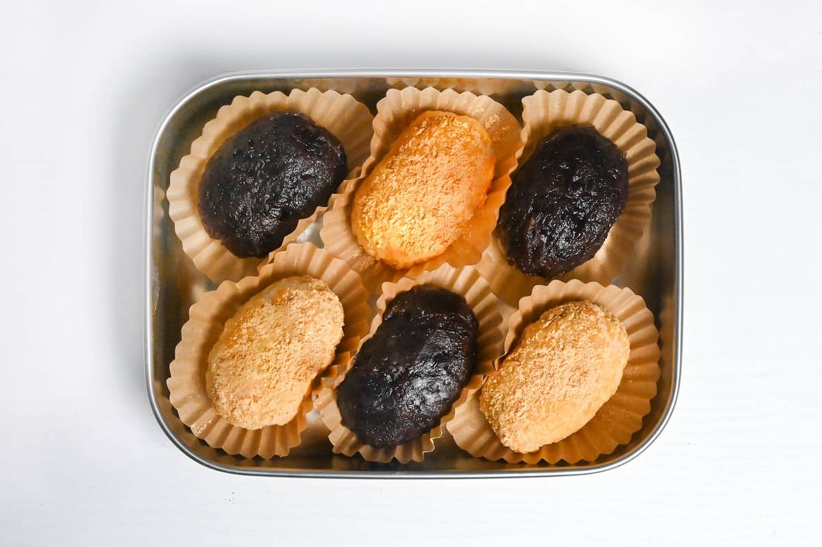 red bean and kinako ohagi in brown cupcake cases in a metal container