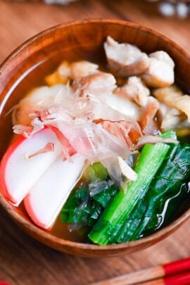 Nagoya style ozoni in a wooden bowl topped with slices of kamaboko (Japanese fishcakes) and bonito flakes