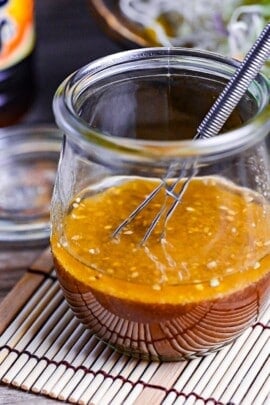 ponzu dressing in a glass jar next to a mixed leaf salad and bottle of yuzu ponzu