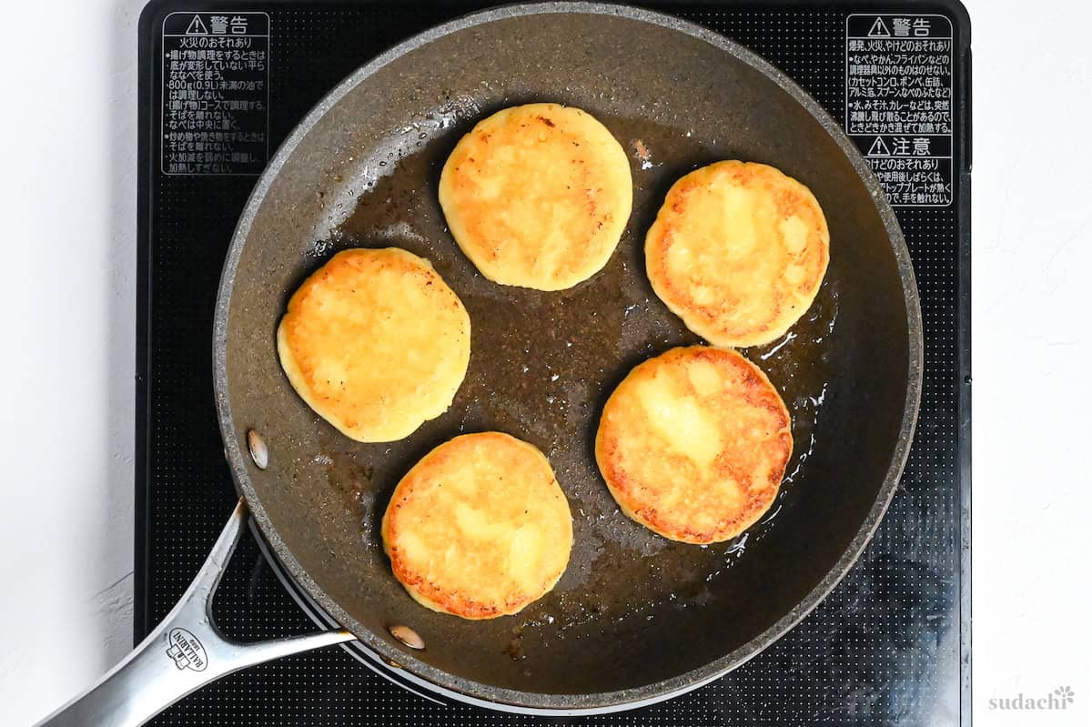 lightly golden and crisp potato mochi in a frying pan on the stove top