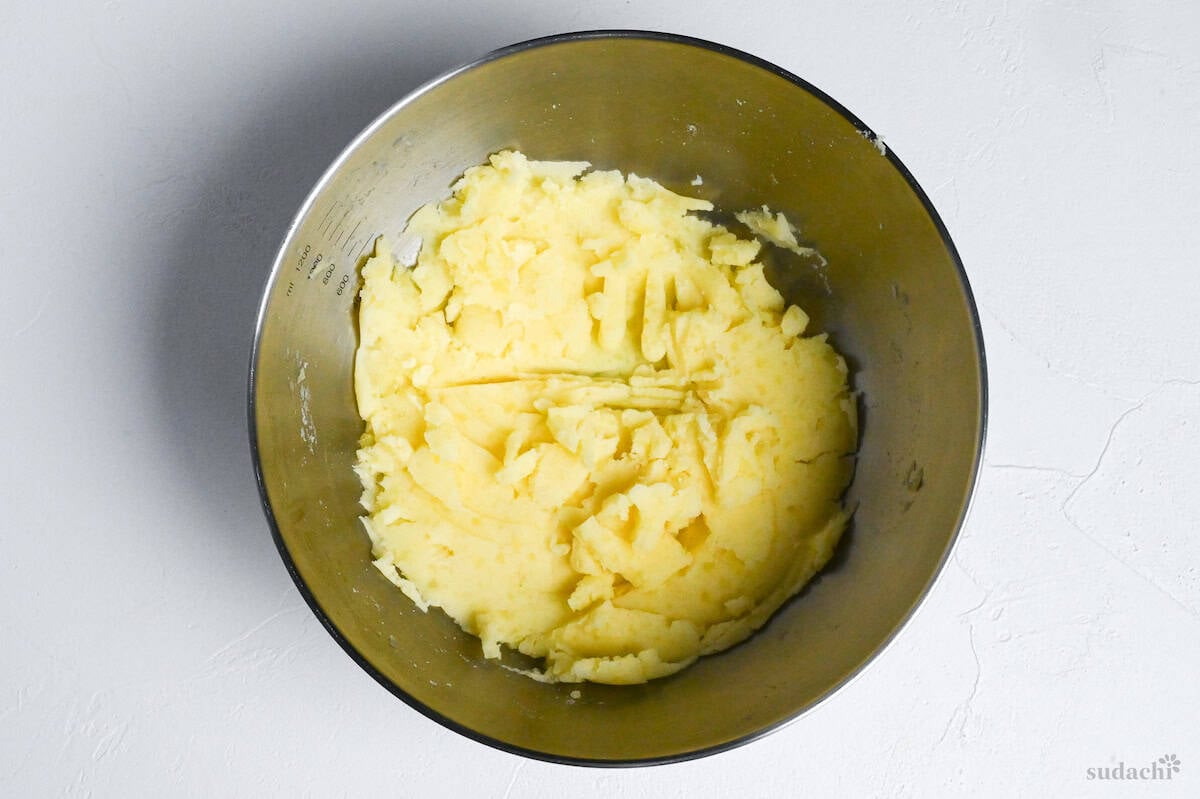 mashed potatoes in a steel mixing bowl on a white background