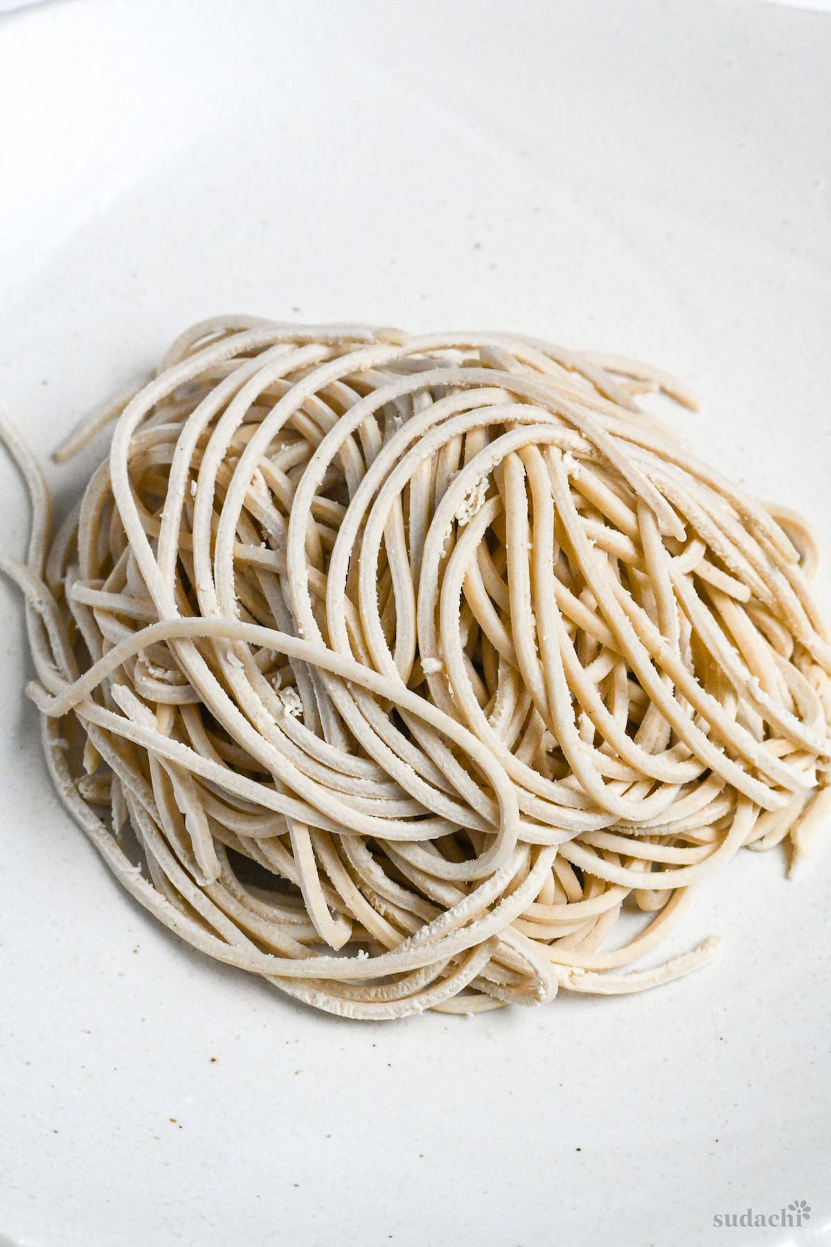 Homemade raw ramen noodles with 2mm thickness on a white plate on a white background