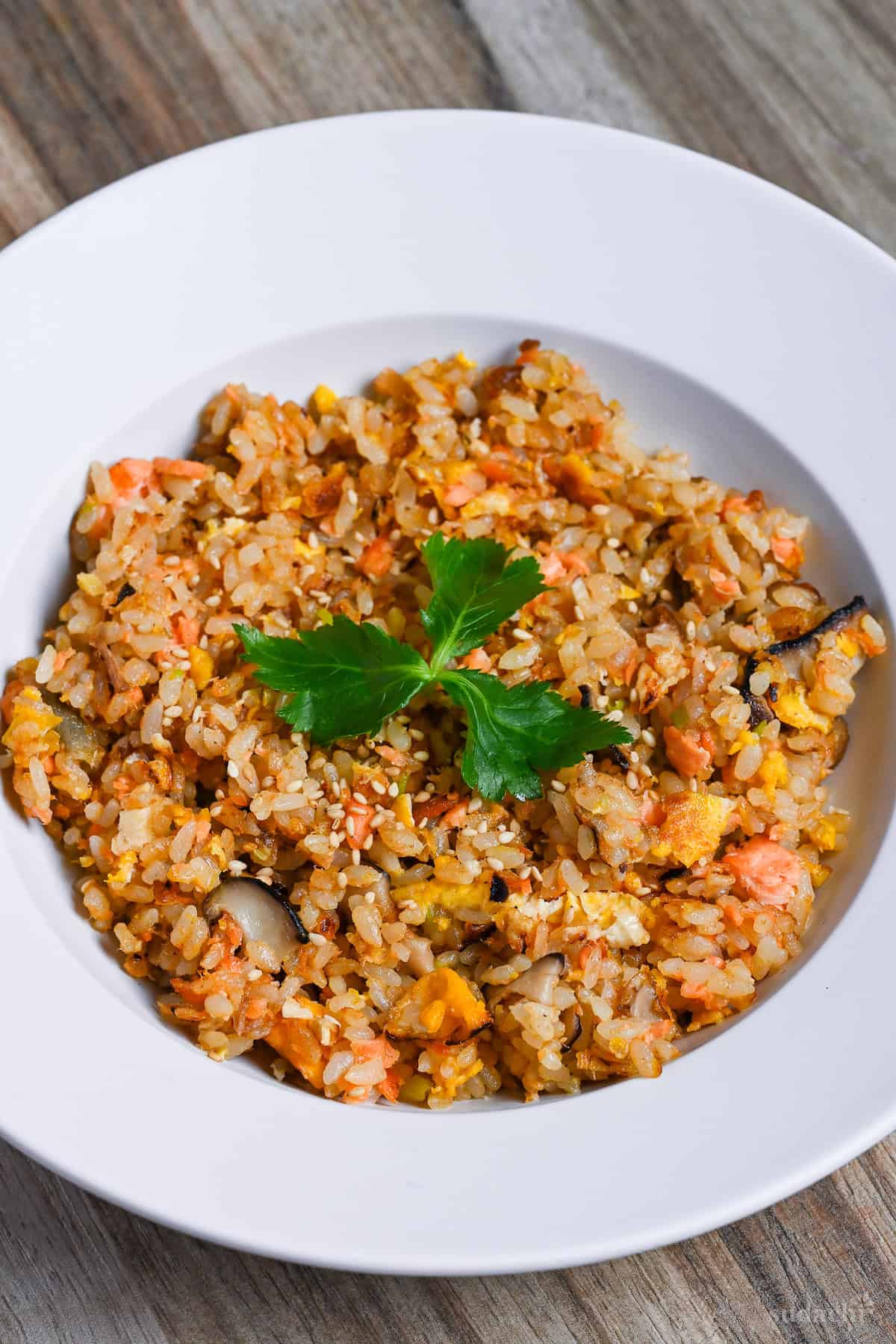 Salmon fried rice served in a white dish and garnished with mitsuba (Japanese wild parsley)