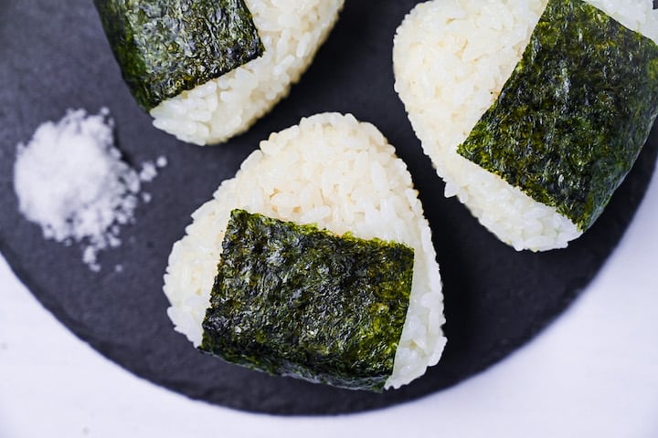 Three salted onigiri rice balls on a round slate plate