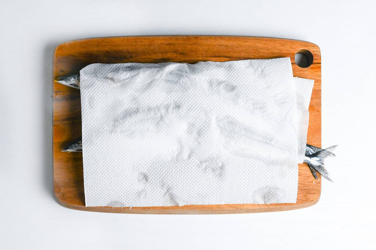 patting pacific saury dry with kitchen paper