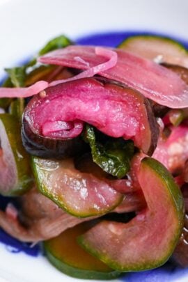 Homemade purple shibazuke pickles made with eggplant, cuucmber, Japanese ginger and ginger in a white dish with eel design close up