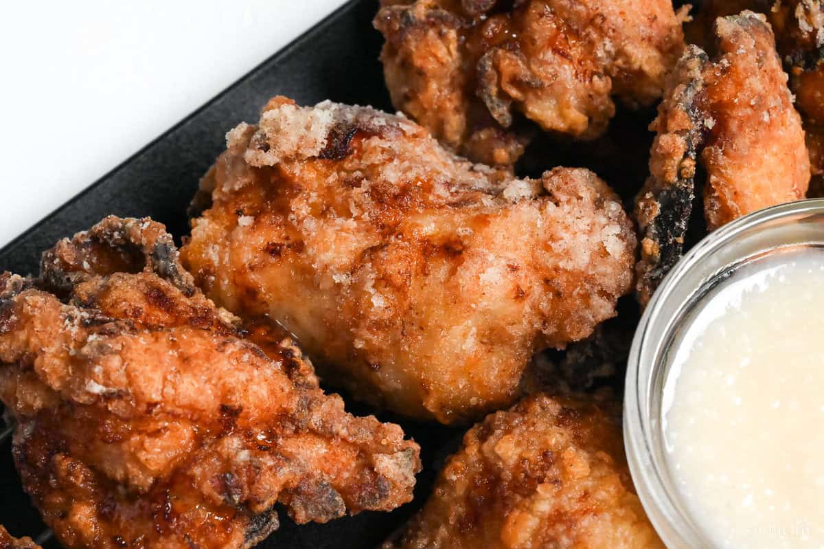 close up of completed shio koji karaage (Japanese fried chicken) on a wire rack with a small clear bowl of shio koji