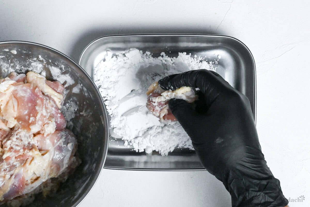 coating shio koji chicken thigh pieces with starch ready for frying