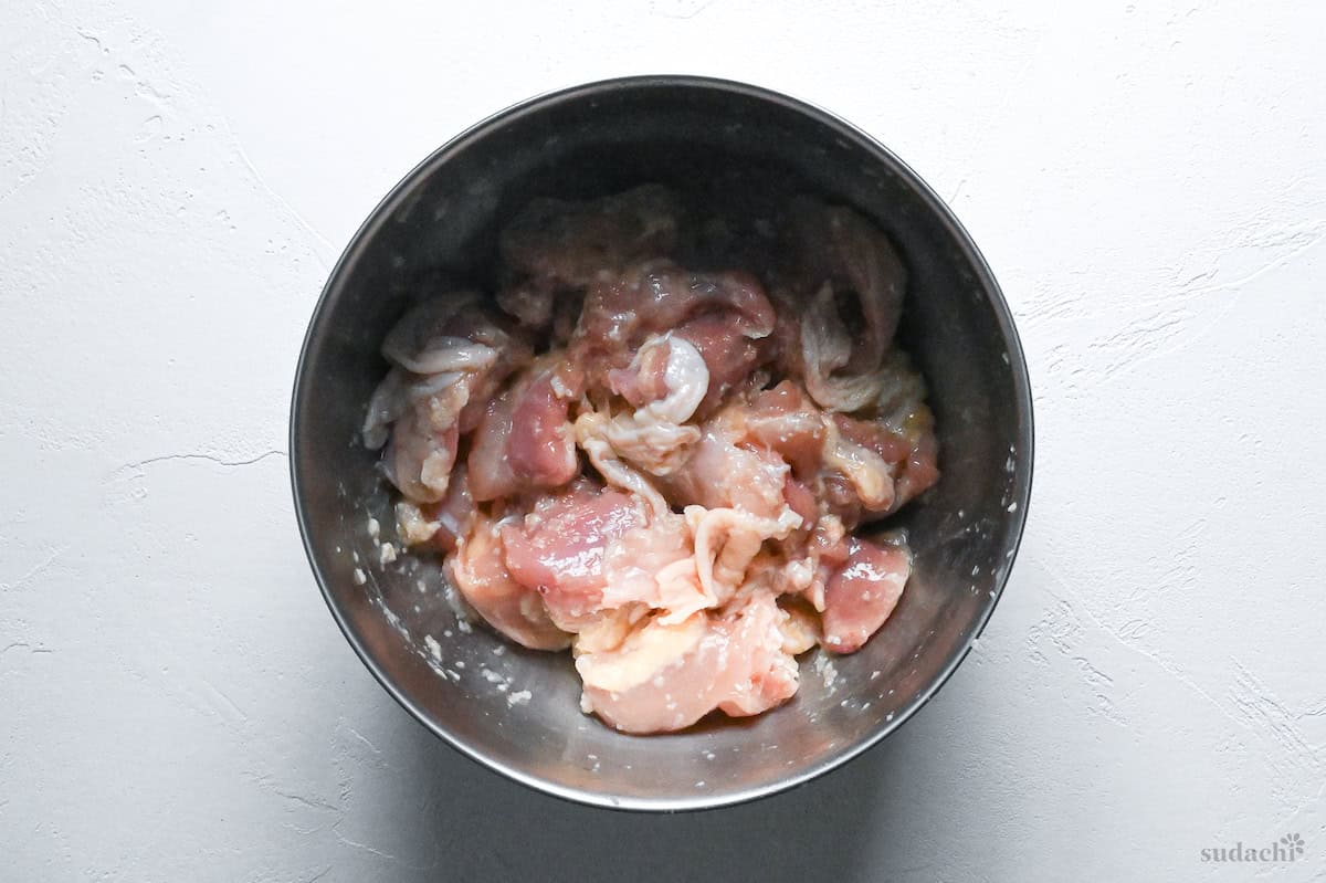 raw chicken thigh pieces coated in koji marinade