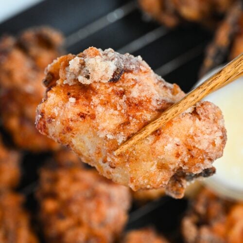 close up of complete double fried shio koji karaage Japanese fried chicken held up with chopsticks