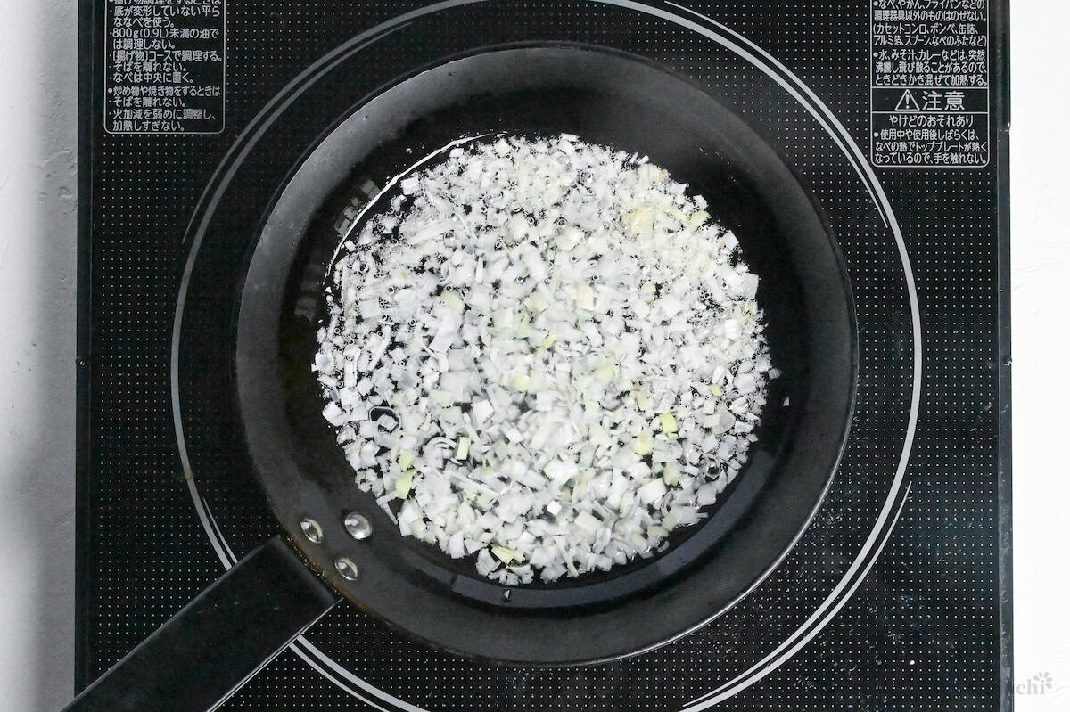 finely chopped Japanese leek (white part) frying in lard in a small frying pan
