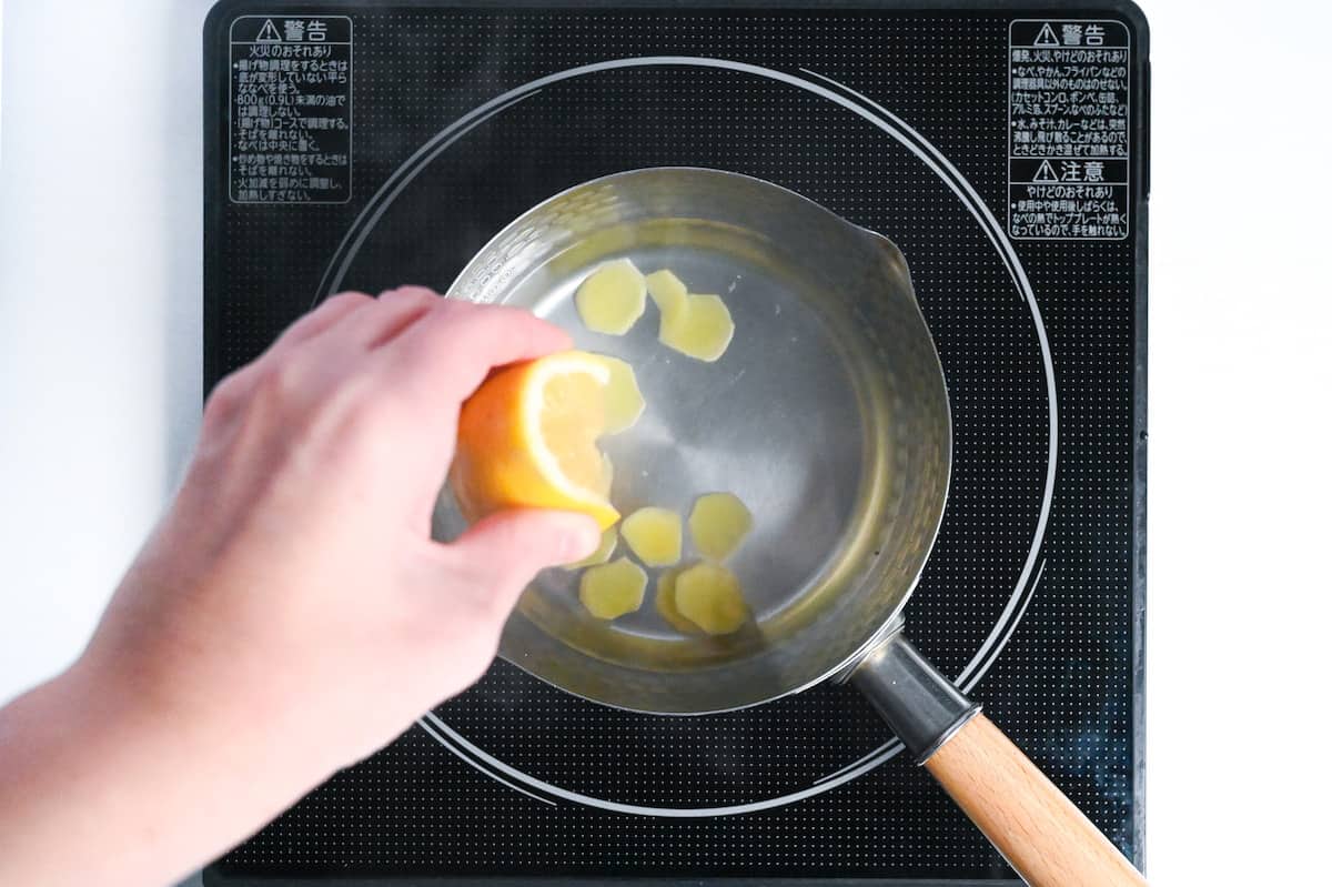 squeezing lemon wedge into shogayu